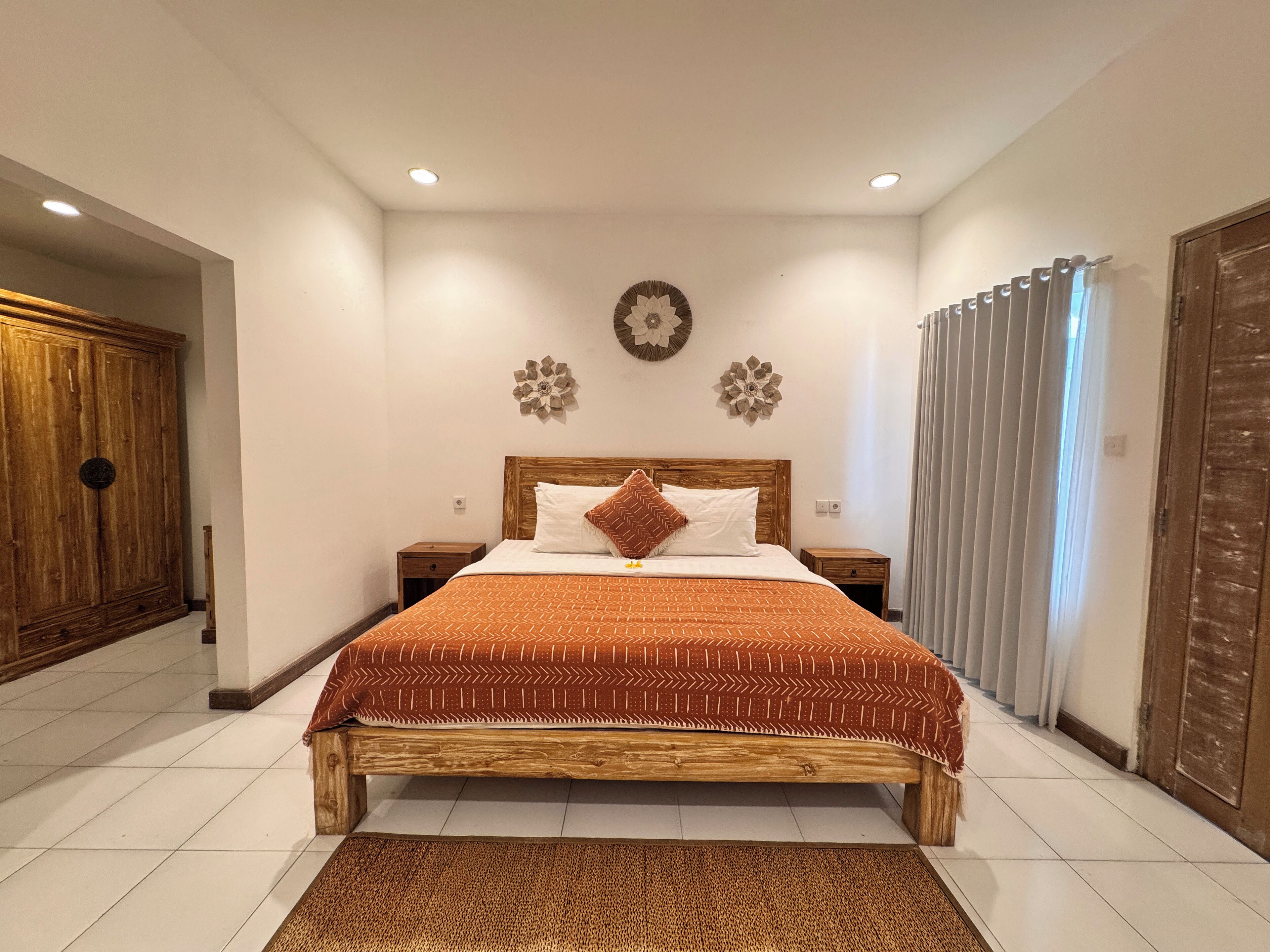 Un dormitorio con cama de madera, paredes blancas y un adorno en la pared.