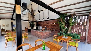 A restaurant with wooden tables and chairs, a brick counter, and hanging plants. - Lubdhaka Canggu (Canggu)
