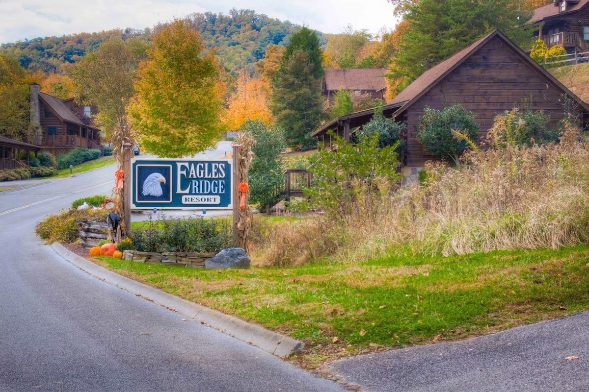 A sign for Eagles Ridge Resort with a rustic cabin and autumn foliage in the background.