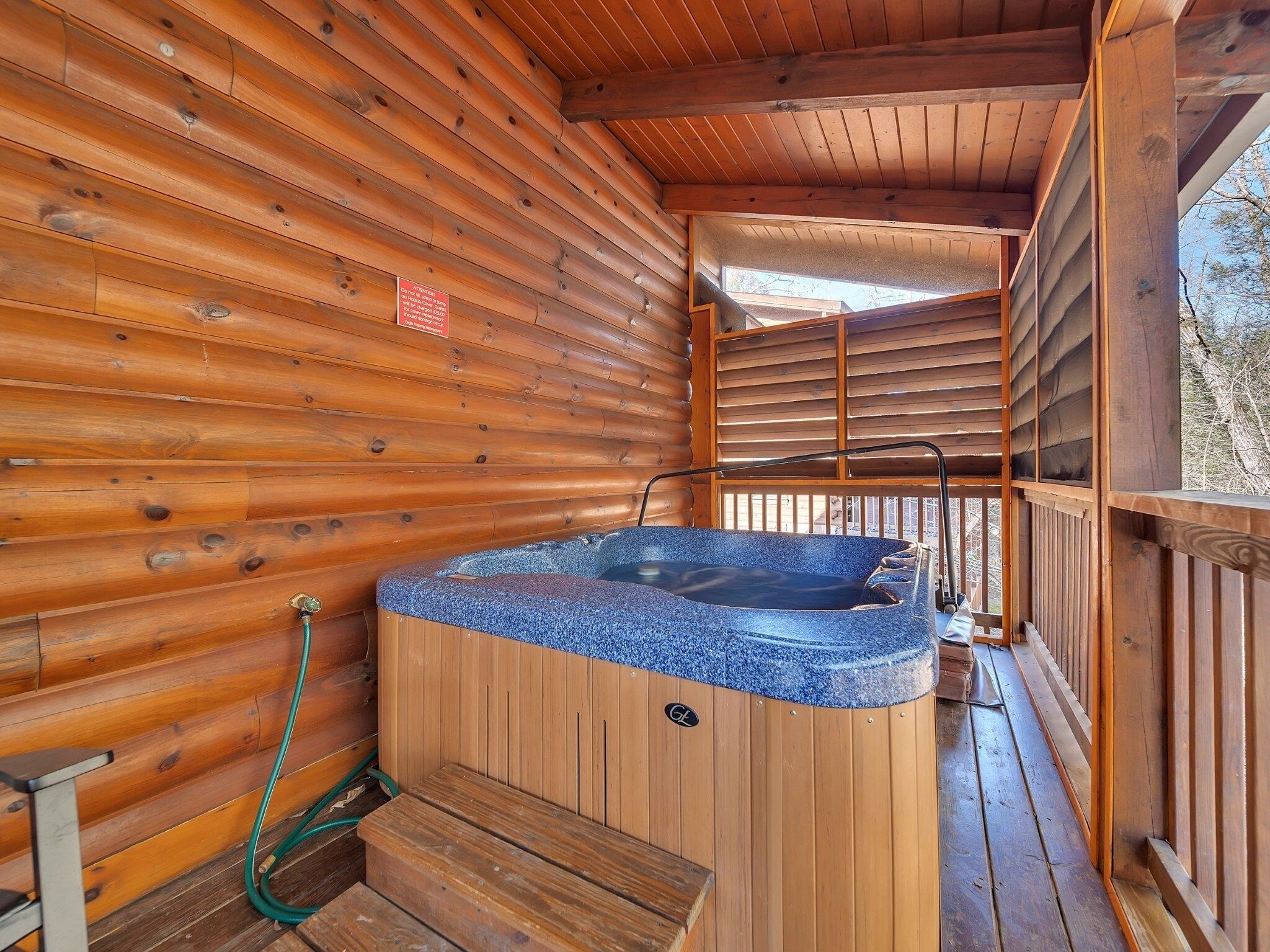 A wooden cabin with a hot tub on the deck.