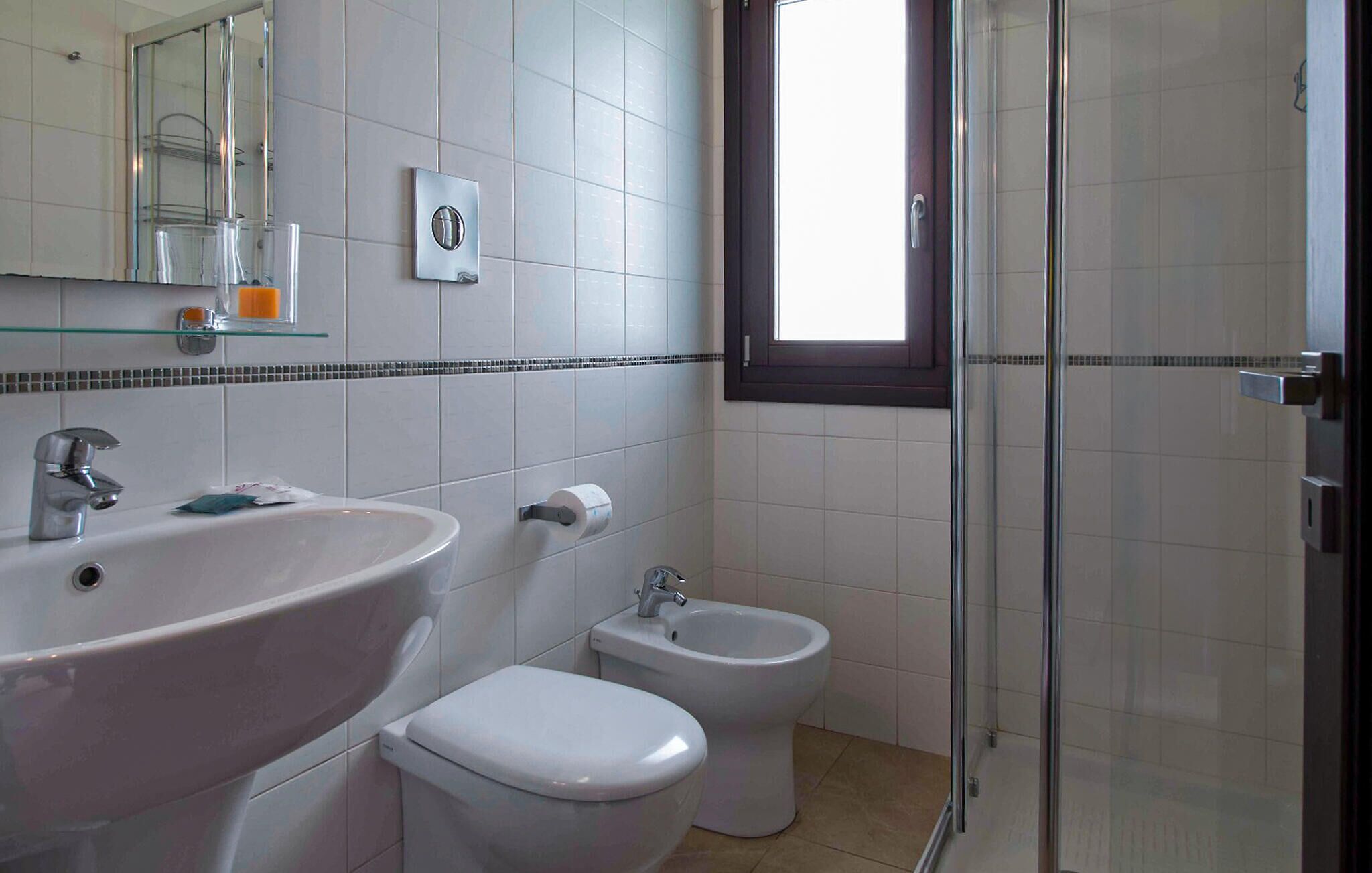 A bathroom with a sink, toilet, bidet, and a glass shower enclosure.