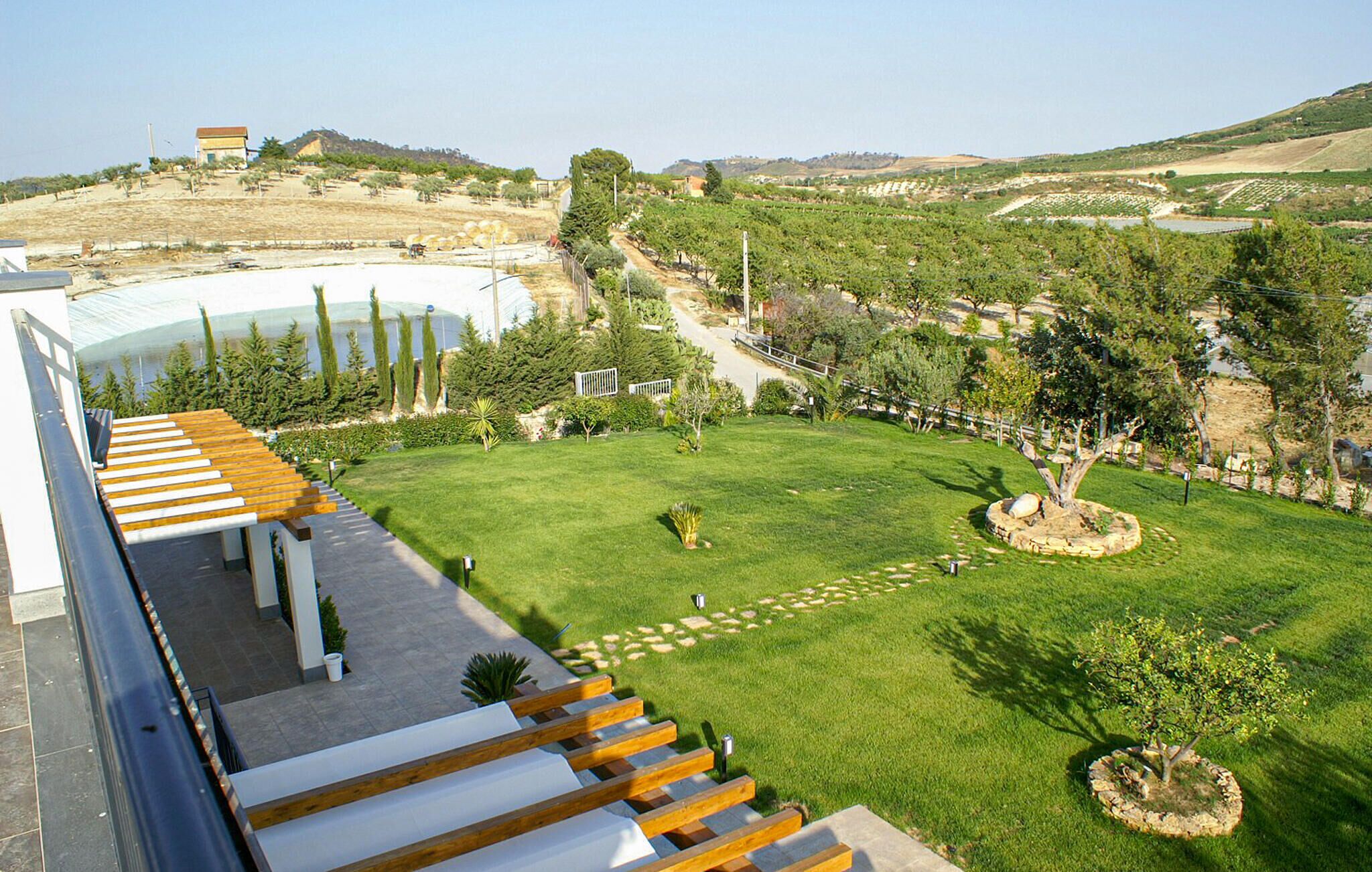 Un hôtel doté d’une terrasse sur le toit offrant une vue sur une pelouse bien entretenue et sur des collines lointaines.