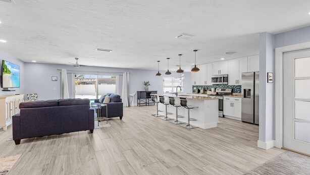 A modern kitchen with white cabinets, stainless steel appliances, and a central island. - Soak Up The Sun - Saltwater Pool, Spacious Fenced-in Backyard, 3 Bedroom Home (Cape Coral)