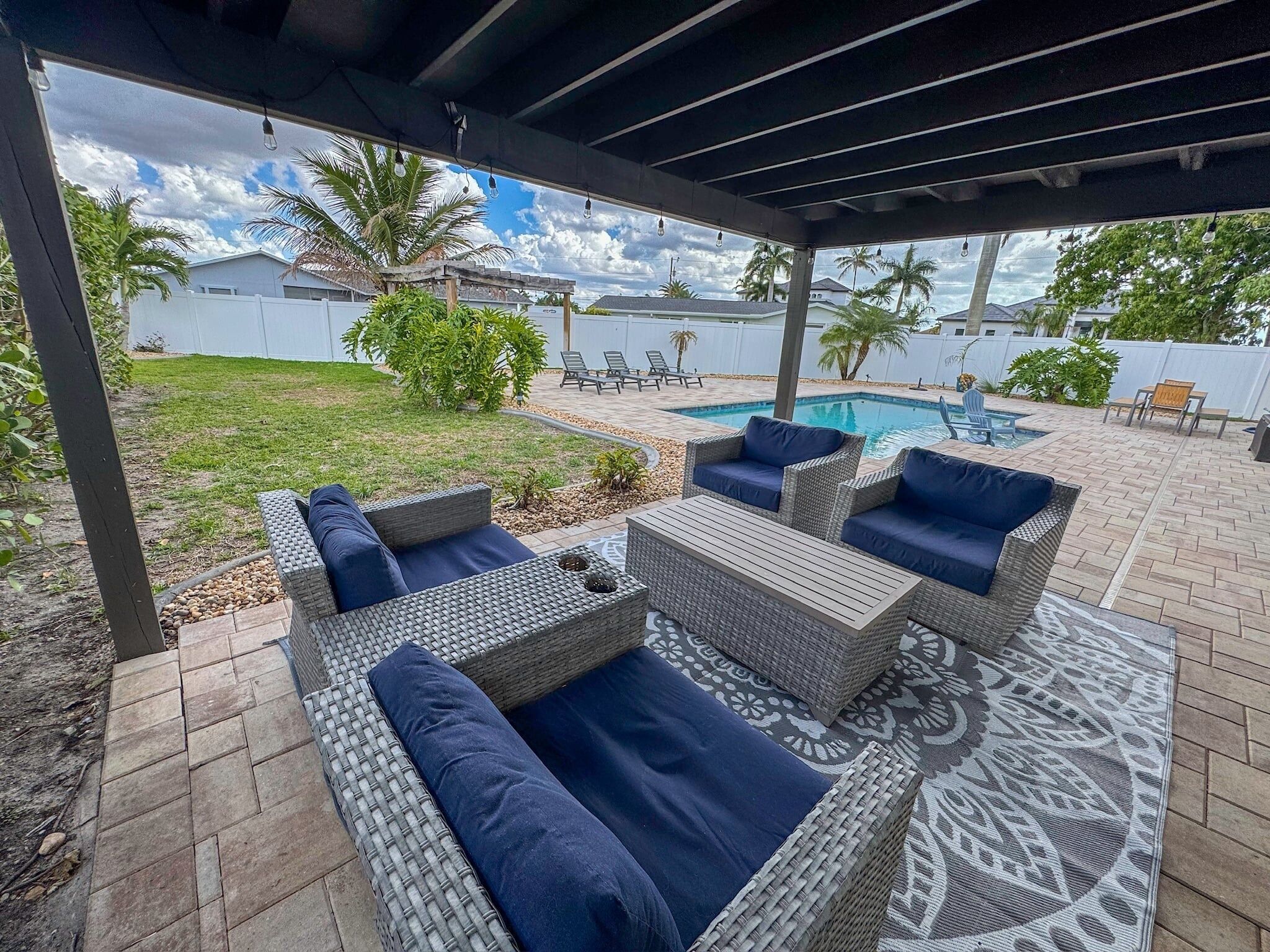 An outdoor patio with wicker furniture and a patterned rug.