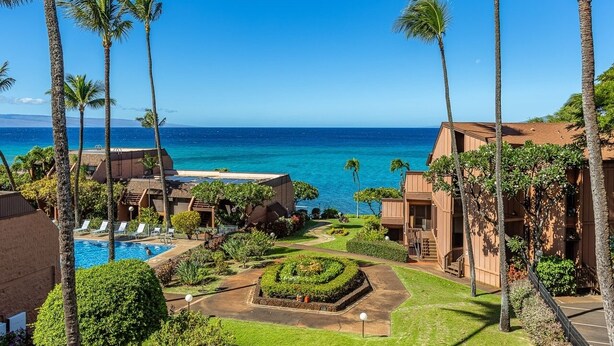 A resort with a swimming pool, palm trees, and a view of the ocean.