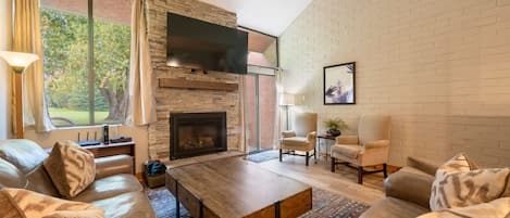 Una sala de estar moderna con chimenea, sofás de cuero, una mesa de centro y un televisor montado en la pared.