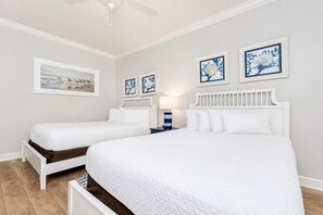 Una camera da letto con due letti, un ventilatore a soffitto e opere d'arte alle pareti.
