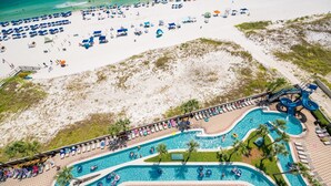 Eine Vogelperspektive zeigt einen Strandort mit Schwimmbad, Liegestühlen und Sonnenschirmen.