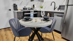 A modern kitchen with marble countertops, a built-in stove, and a stainless steel refrigerator. - Elegant|Spacious|King Bed|Fireplace|Ravine View (Edmonton)