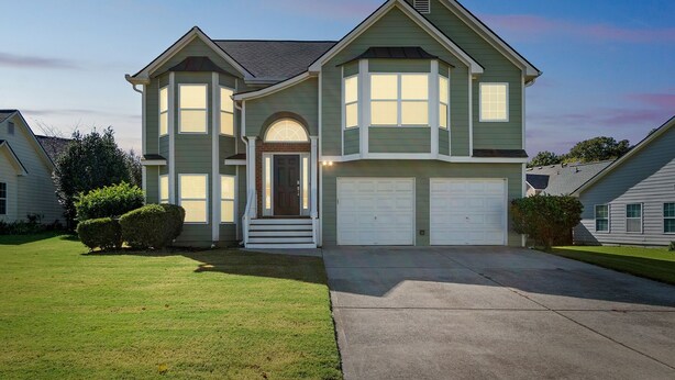 A two-story house with a front entrance, a garage, and a well-maintained lawn.