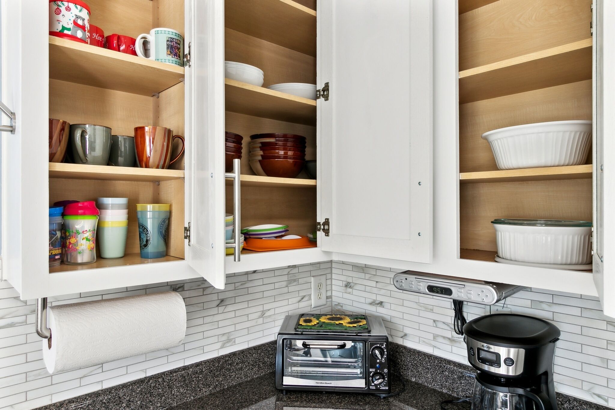 A kitchen with open cabinets displaying various dishes and cookware.