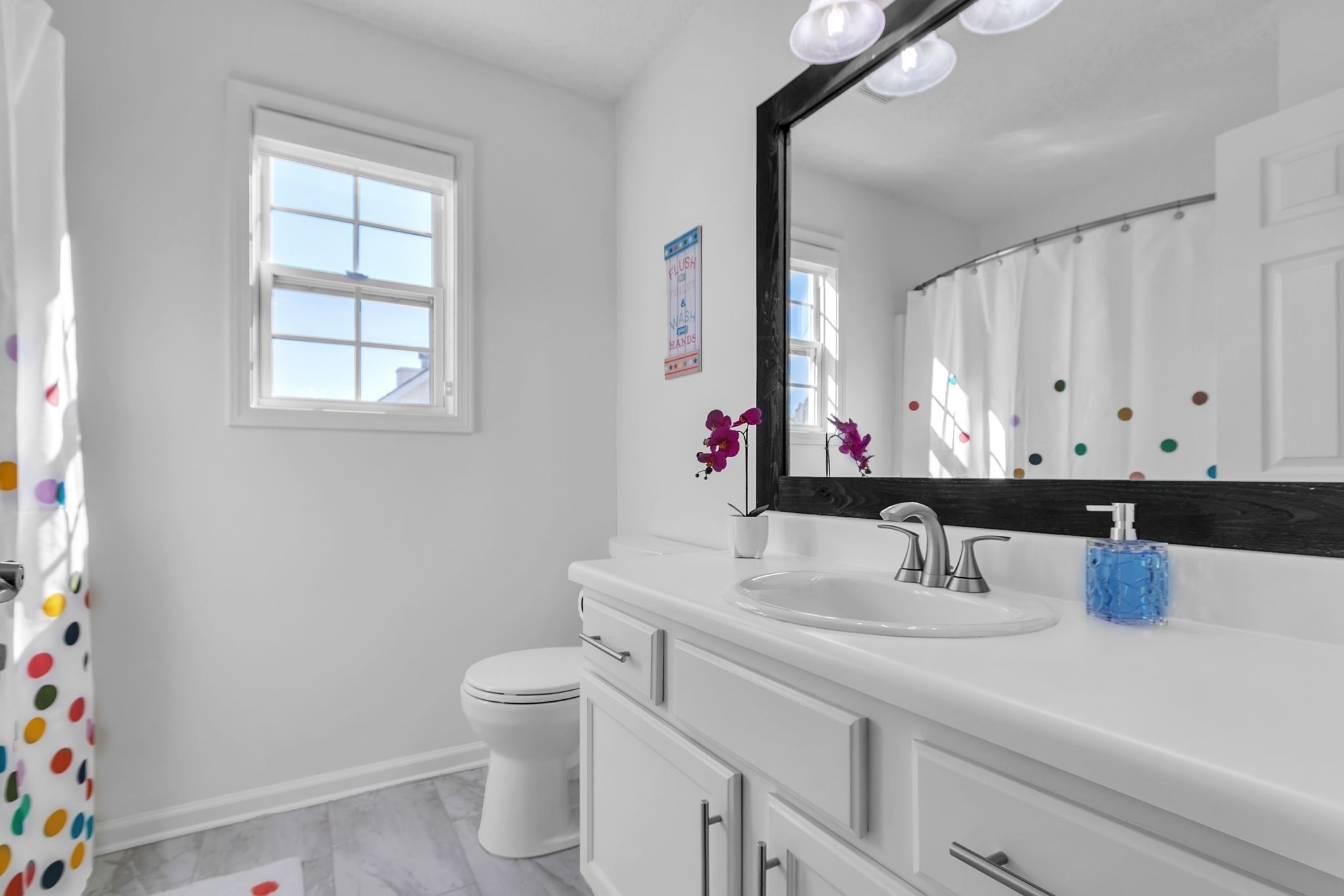A bathroom with a white sink, mirror, and toilet.