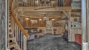 Ein rustikales Interieur mit einer Holztreppe, einer Erkerzone, einem Windmühlenmodell und einem alten, roten Koffer.
