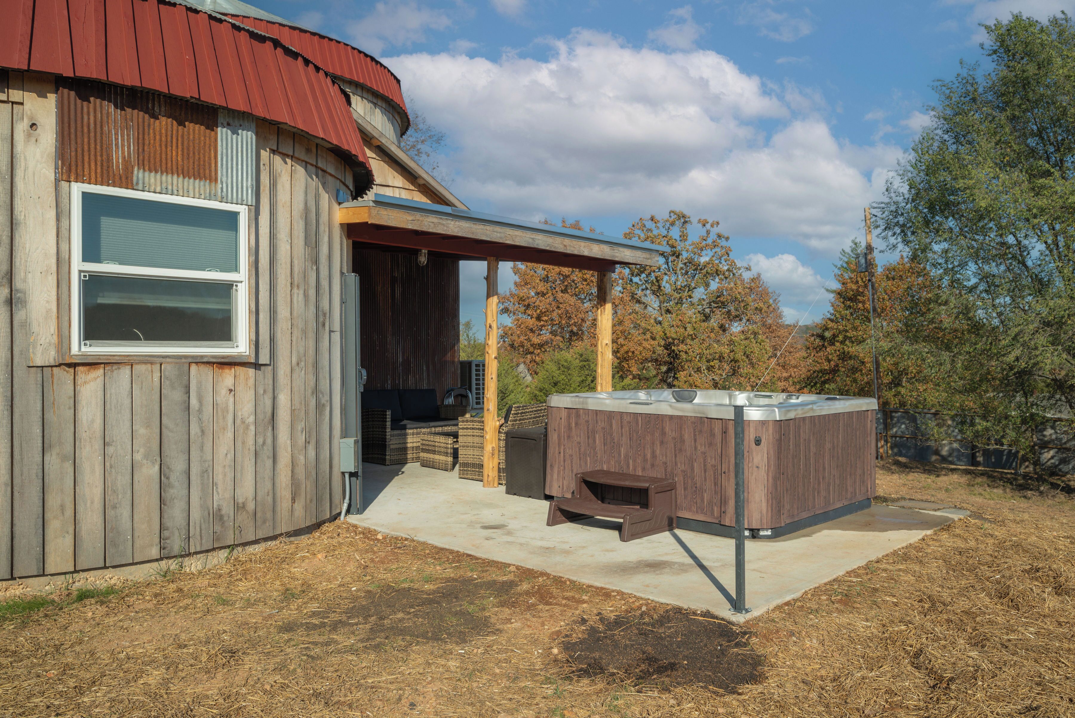 A rustic wooden building with a hot tub and outdoor seating area.