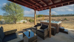 Eine Terrassengruppe im Freien mit Korbmöbeln, einem Whirlpool und Blick auf die Landschaft.