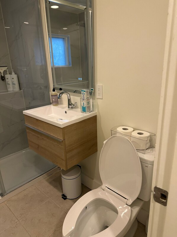 Une salle de bain moderne avec un lavabo blanc, un miroir et des toilettes.