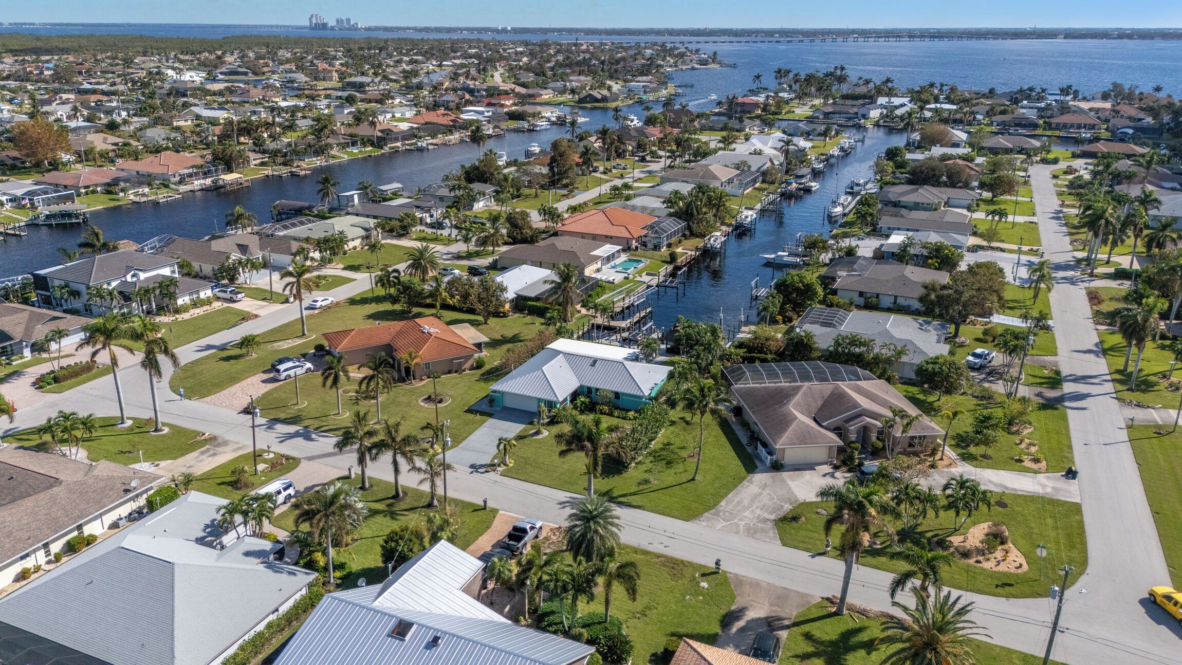 A residential area with houses, palm trees, and a marina.