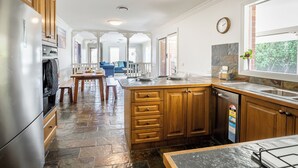 A kitchen with wooden cabinets, a granite countertop, a built-in dishwasher, and a stone backsplash. - Spacious | Pet Friendly | Ping Pong Table | Near Beach (Ocean Grove)
