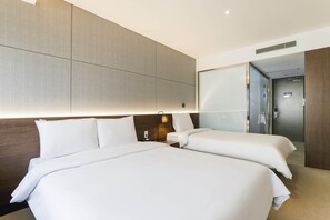 A hotel room with two beds, a nightstand, a lamp, and a door leading to a bathroom. - HOTEL ELORA (Yongin)