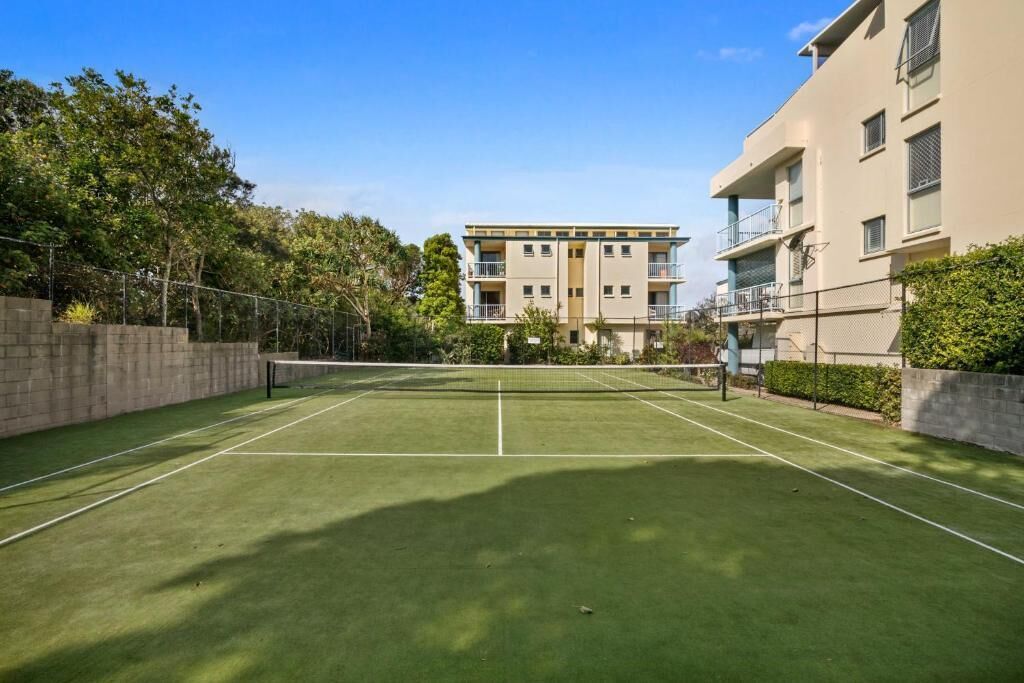 An outdoor tennis court surrounded by apartment buildings.