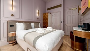A hotel room with a large bed, bedside tables, a desk, and a mirror. - GuestReady – Chic Retreat in Fitzrovia (London)