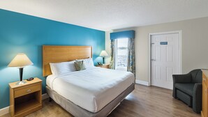 A hotel room with a large bed, bedside tables with lamps, a chair, and a door. - Spacious One Bedroom Condo (Virginia Beach)