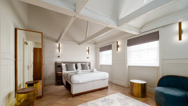 A bedroom with a large bed, a blue sofa, and a wooden floor. - GuestReady – Top Floor Central London Getaway (London)