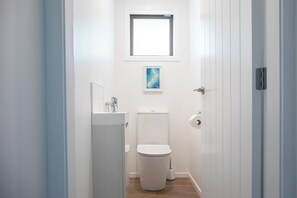 Kapea kylpyhuone, jossa on wc, pesuallas ja ikkuna wc:n yläpuolella.