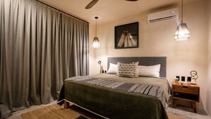 Ein Hotelzimmer mit Bett, Nachttisch, Deckenventilator und einem Fenster mit Vorhängen.