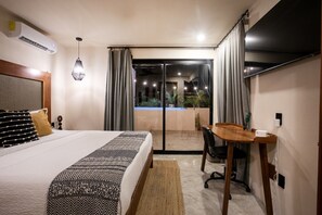 A hotel room with a bed, a desk, a chair, an air conditioning unit, and a view of the outside. - Luxury Penthouse w/ Jungle Views (Tulum Municipality)