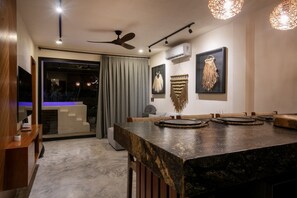A modern dining area with a large table, ceiling fan, and wall-mounted air conditioning unit. - Luxury Penthouse w/ Jungle Views (Tulum Municipality)