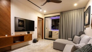 Ein modernes Wohnzimmer mit Flachbildfernseher, einer Holz-Unterhaltungseinrichtung, einem grauen Sofa und einem Deckenventilator.