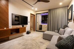 A modern living room with a flat-screen TV, wooden entertainment unit, grey sofa, and a ceiling fan. - Tulum Penthouse · 3 King Suites · Rooftop Pool (Tulum Municipality)
