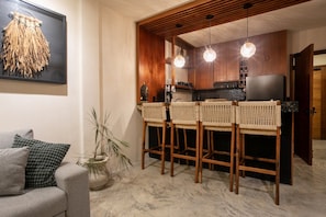 A modern kitchen with wooden cabinets, a black countertop, and three hanging pendant lights.