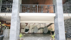 Eine moderne Lobby mit einer zentralen Treppe, Topfpflanzen und einem Hängesessel.