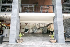 A modern lobby with a central staircase, potted plants, and a hanging chair. - Tulum Penthouse · 3 King Suites · Rooftop Pool (Tulum Municipality)