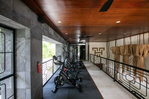 A gym corridor with exercise equipment, a fire extinguisher, and a view of greenery outside. - Tulum Penthouse · 3 King Suites · Rooftop Pool (Tulum Municipality)