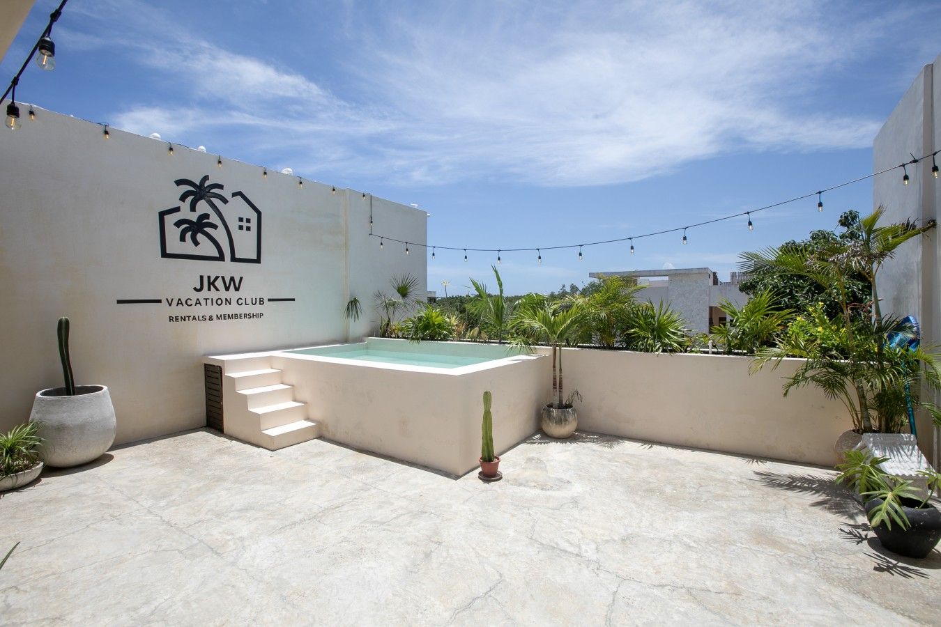 Une terrasse sur le toit avec une piscine, un escalier et une enseigne indiquant « JKW Vacation Club Rentals & Membership ».