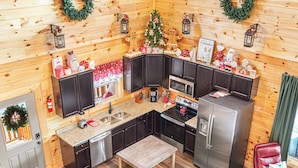 A modern kitchen with wooden walls, stainless steel appliances, and festive decorations. - XmasCabins by SmokyStays - Christmas Themed Year Round (Pigeon Forge)
