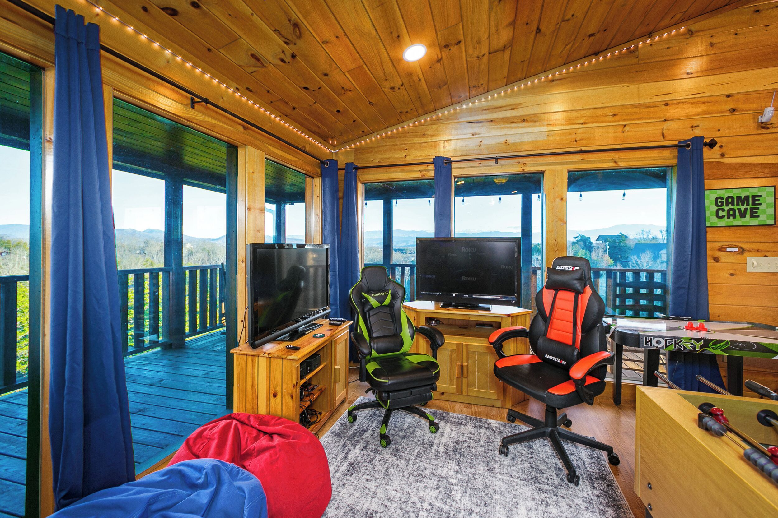 A wooden deck with a TV, gaming chairs, and a pool table.
