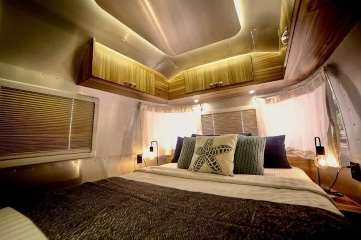 A bedroom with a bed, bedside tables, curtains, and a window.