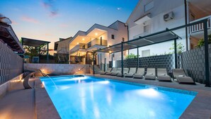 A modern outdoor swimming pool with lounge chairs and a covered seating area. - 6 bedroom stunning home in Podglavica (Podglavica)