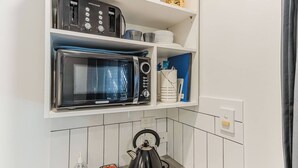 A compact kitchen with a built-in microwave, toaster, and kettle. - Lilys Studio (Kingscliff)