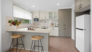 Una cocina moderna con una isla central, taburetes de bar, un refrigerador y un microondas.