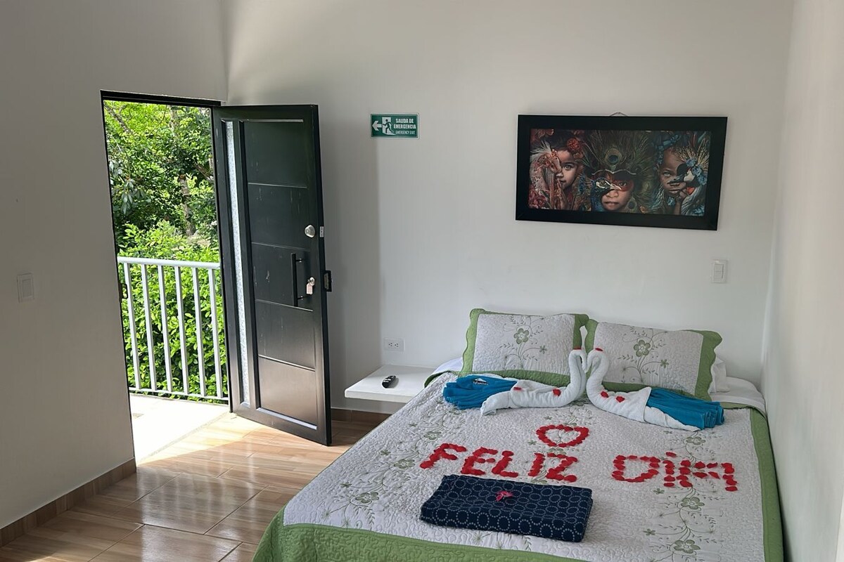 A bedroom with a bed, a painting, a door, and a balcony.