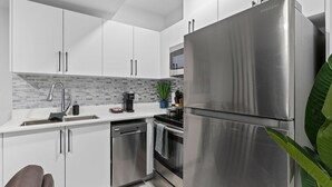 A modern kitchen with stainless steel appliances, white cabinetry, and a tiled backsplash. - Classy | Stylish | 13 min to West Edmonton Mall (Edmonton)
