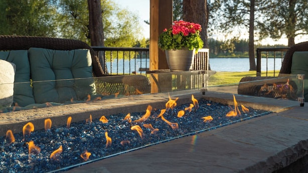 An outdoor seating area with a fire feature, a potted plant, and a view of a body of water. - Historic  Gilchrist Waterfront Resort (Crescent)