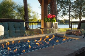 Un espacio de estar al aire libre con una chimenea, una planta en maceta y vistas a un cuerpo de agua.