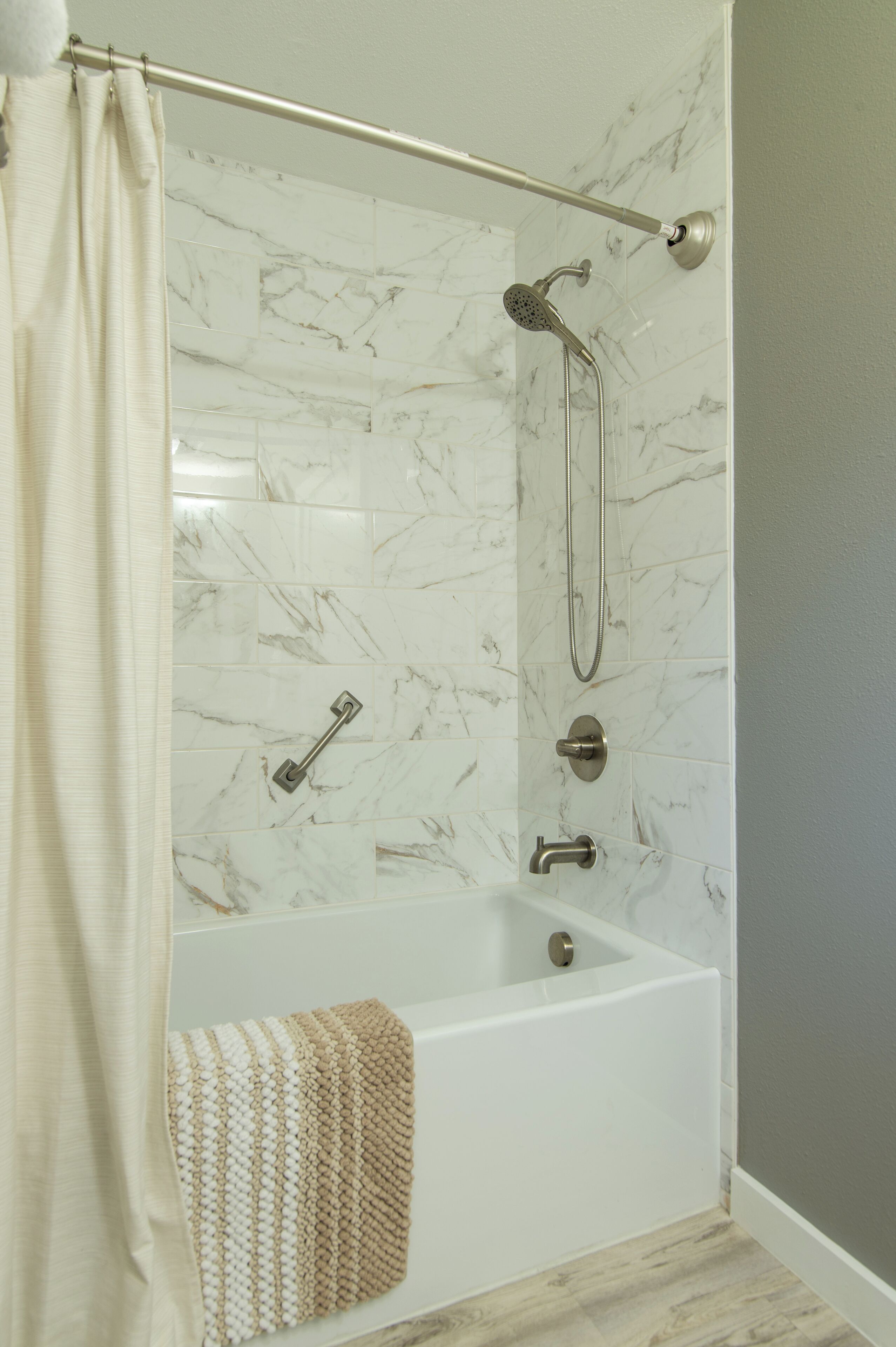Une salle de bain moderne équipée d’une baignoire, d’une douche et d’une barre d’appui.