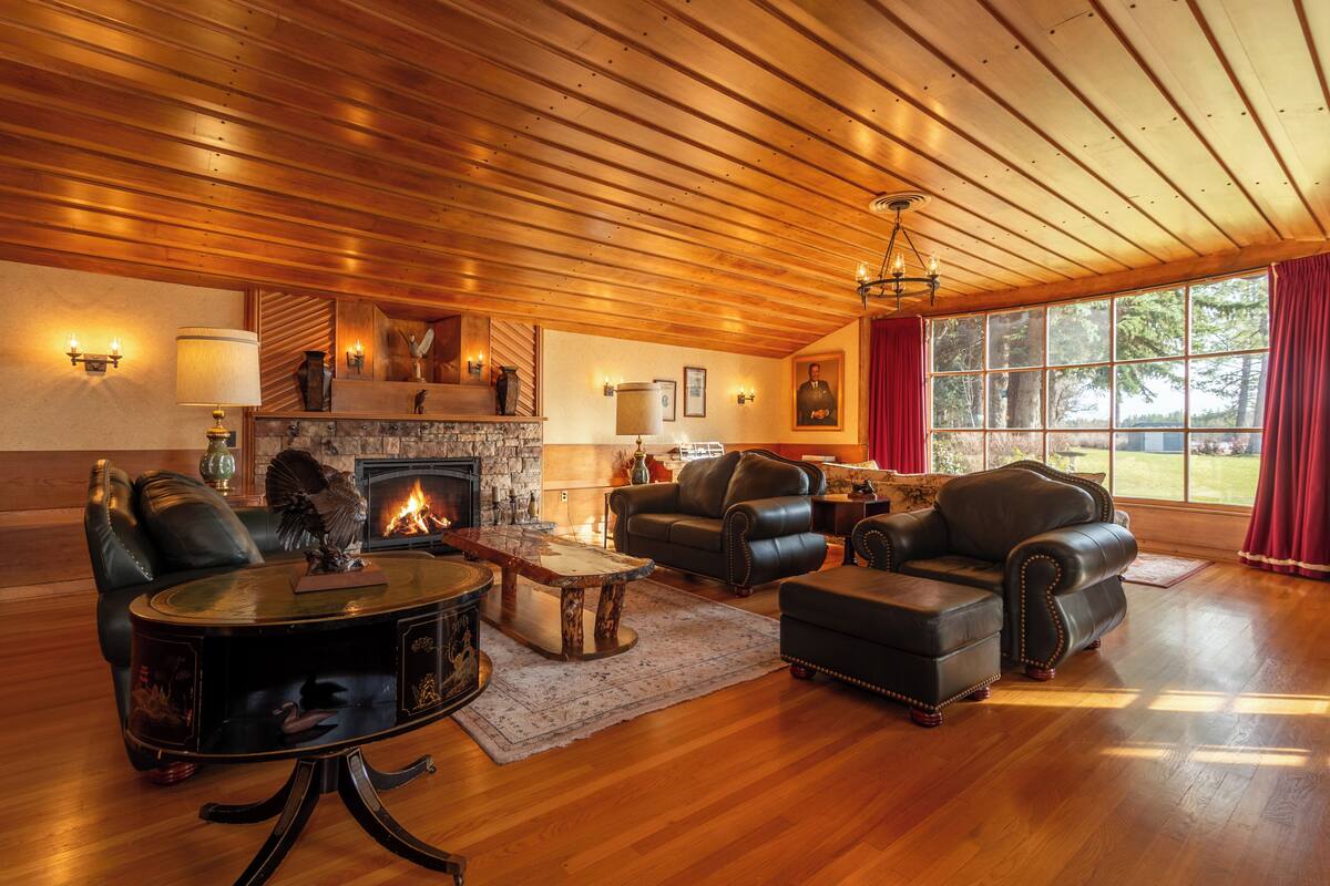 A spacious living room with leather furniture, a fireplace, and large windows.